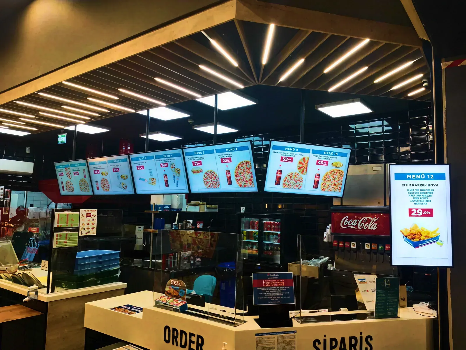 Several Domino's menu boards above the counter, each showing live menu content and pricing
