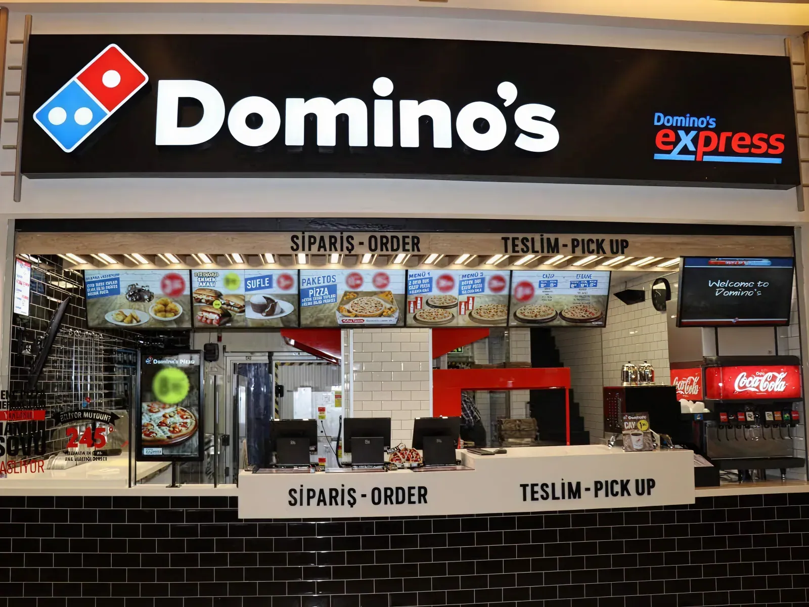 A Domino's store counter with OmmaSign menu boards mounted overhead