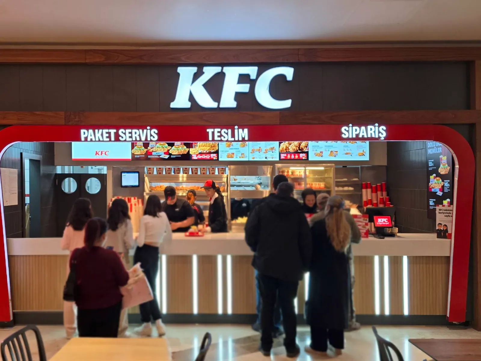 A KFC counter with OmmaSign menu screens mounted overhead